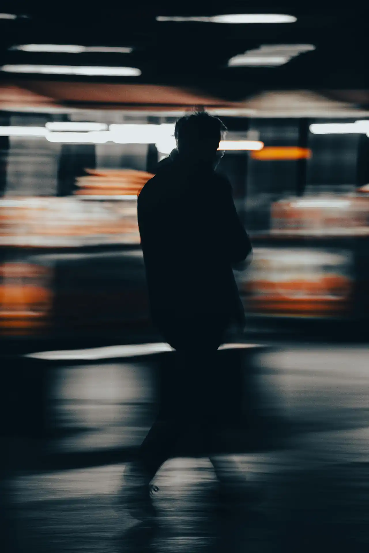 A figure crossing the street seen through a rain-streaked window at dusk