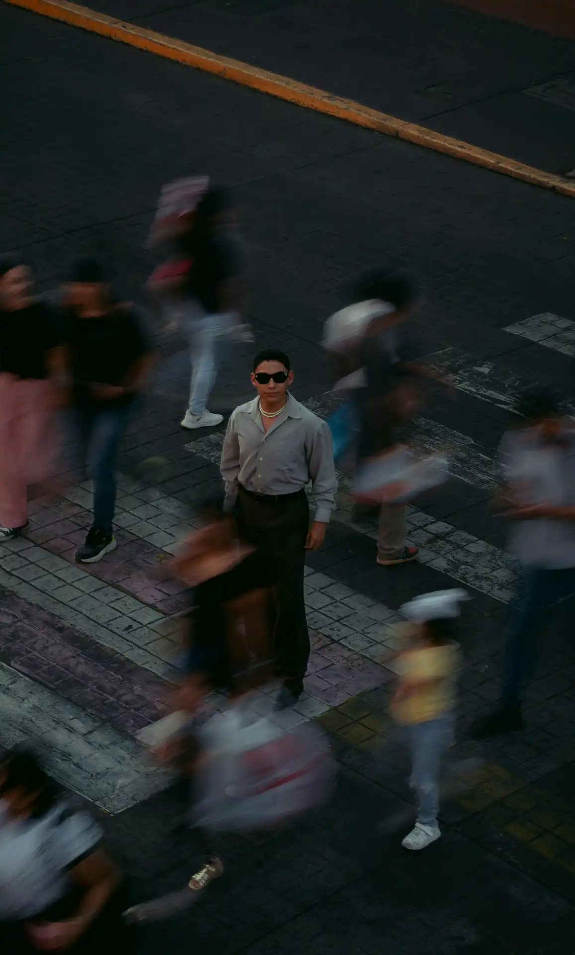 A man standing still in sharp focus while a crowd moves in motion blur around him